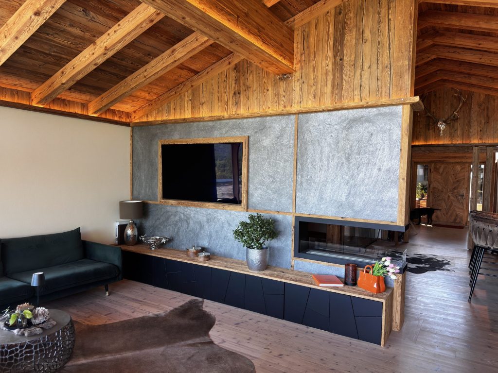 Gemütliches Wohnzimmer mit Holzdecke, freiliegenden Balken und gedämpfter Beleuchtung.