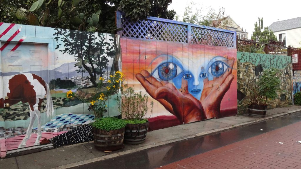 Buntes Wandbild mit Augen und Händen an einer Wand.